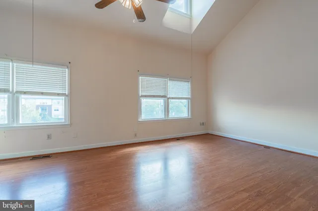 an empty room with wooden floor cabinet and windows