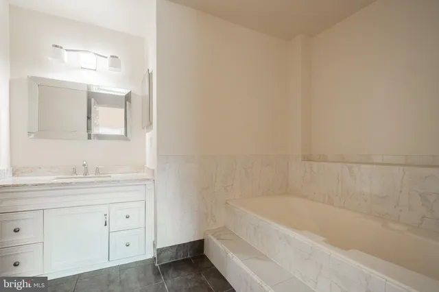 a bathroom with a bathtub a mirror a sink and vanity