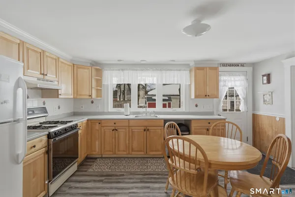 a kitchen with stainless steel appliances granite countertop a stove top oven a sink dishwasher and white cabinets with wooden floor