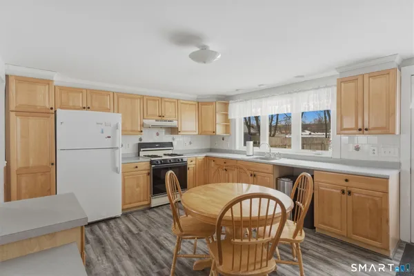 a kitchen with stainless steel appliances granite countertop a refrigerator a stove a sink a dining table and chairs