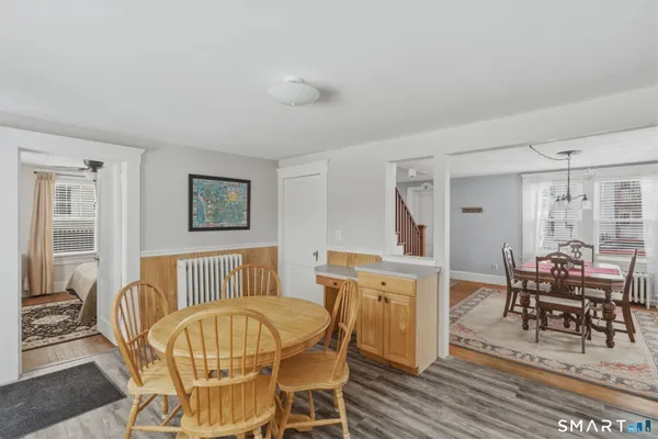 a living room with furniture and a dining table with wooden floor