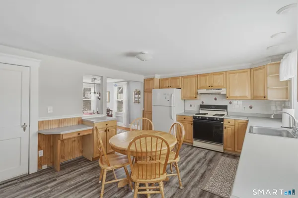 a kitchen with stainless steel appliances granite countertop a stove top oven a sink dishwasher a dining table and chairs with wooden floor