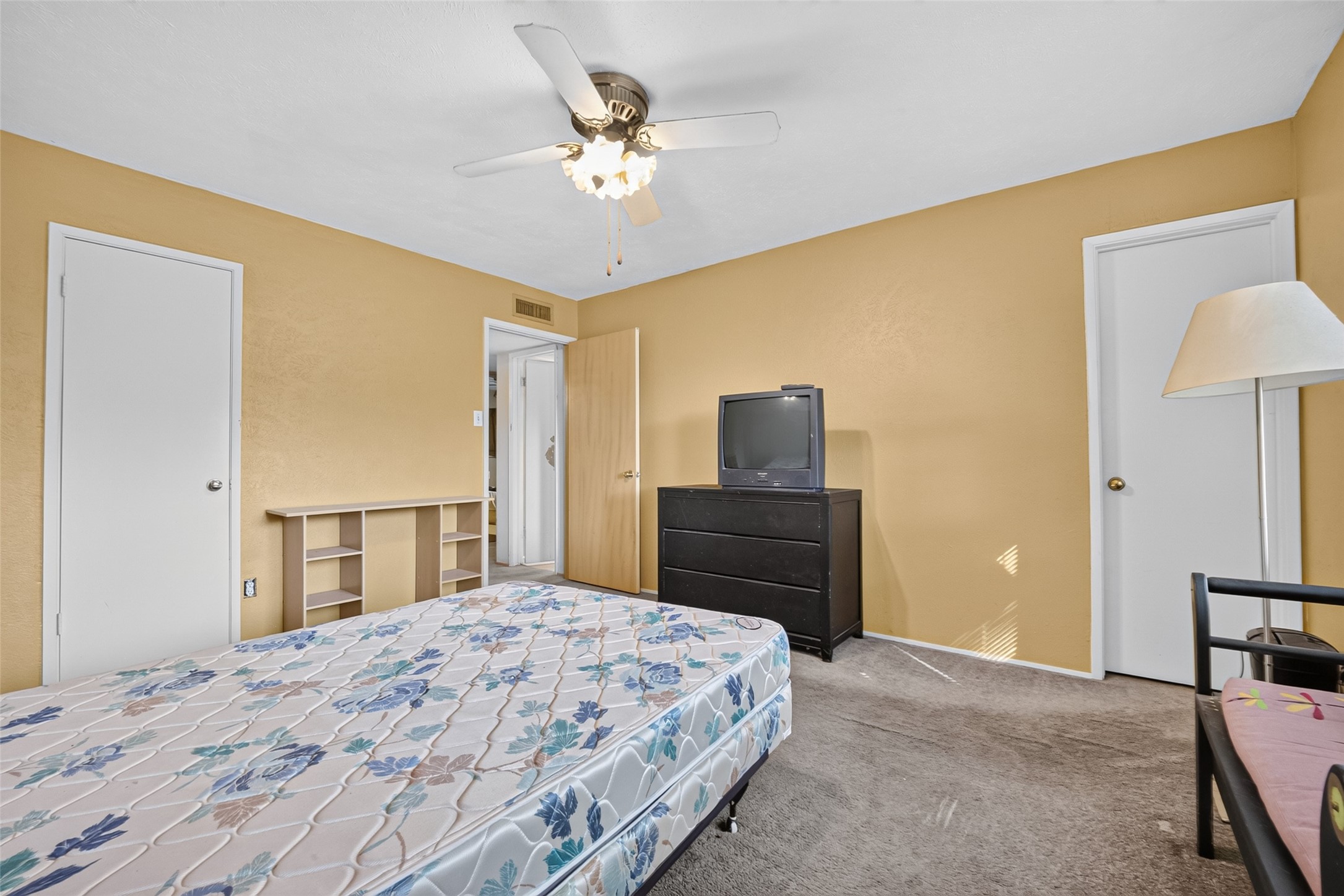 22926 Millgate Drive Spring, TX 77373 - Photo 26 of 34 This bedroom features warm yellow walls, a ceiling fan, and plenty of natural light. It includes a closet, a wooden dresser, and built-in shelving for storage.