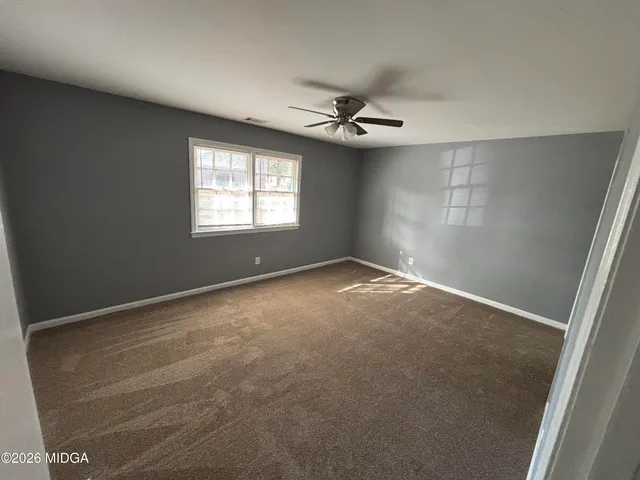 an empty room with windows and fan