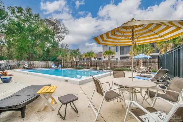 a view of a swimming pool with a table and chairs under an umbrella