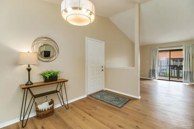 a view of an empty room with wooden floor and windows