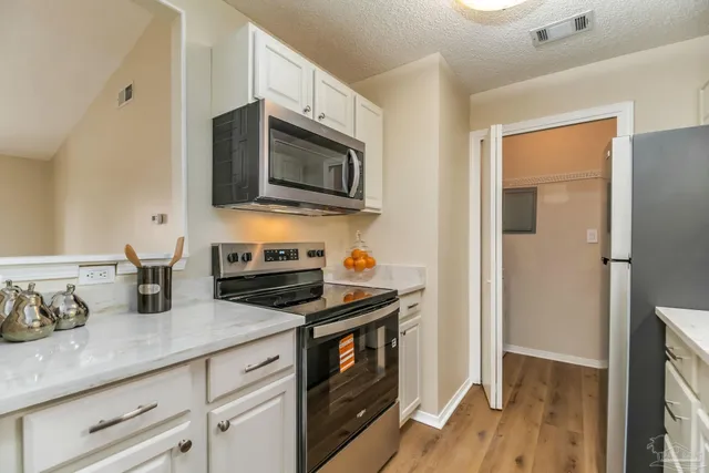 a kitchen with granite countertop cabinets stainless steel appliances and wooden floor
