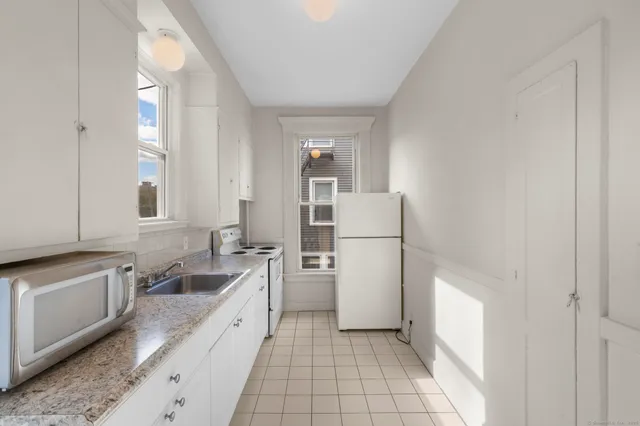 a large white kitchen with a stove a refrigerator and a sink