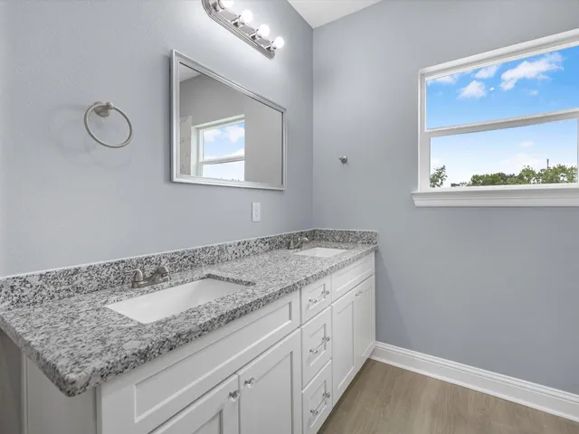 a bathroom with a granite countertop sink and a window