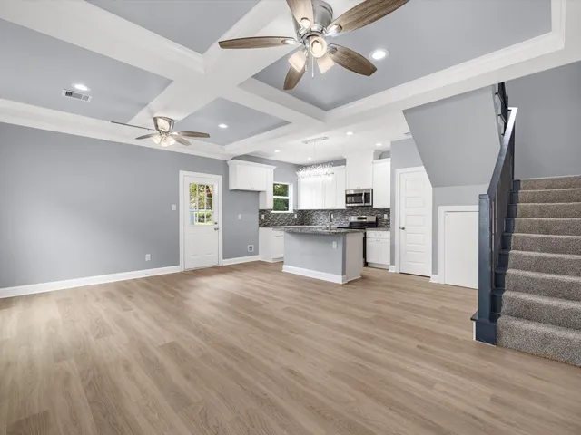 a view of an empty room with wooden floor and a ceiling fan