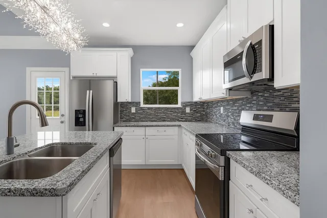 a kitchen with granite countertop a sink stainless steel appliances and cabinets
