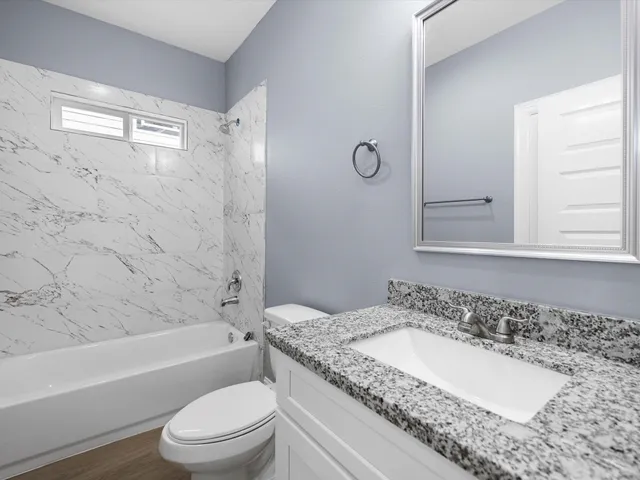 a bathroom with a granite countertop sink a toilet and shower