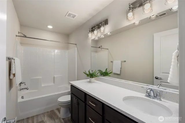 a bathroom with a granite countertop sink a toilet a mirror a bathtub and shower