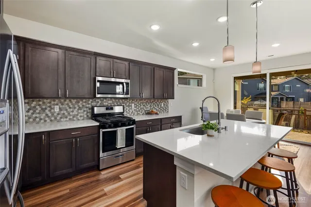 a kitchen with a sink a stove a microwave and wooden floor