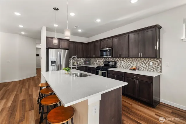 a kitchen with kitchen island a stove a sink a refrigerator and cabinets