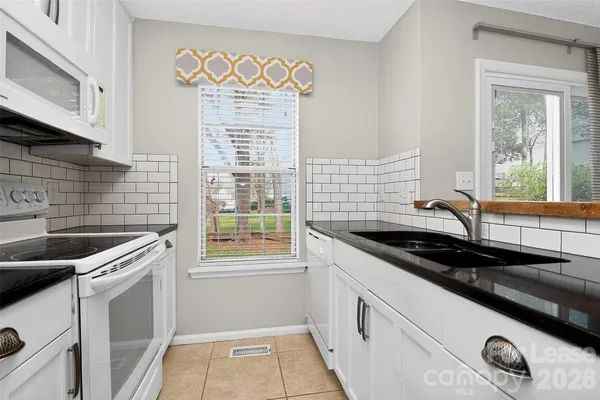 a kitchen with granite countertop a sink a stove a microwave and cabinets