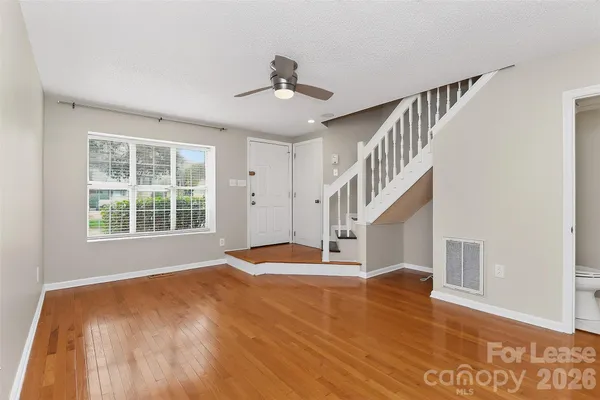 a view of an empty room with wooden floor and a window