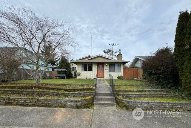 a view of a white house in a big yard with a small yard and plants
