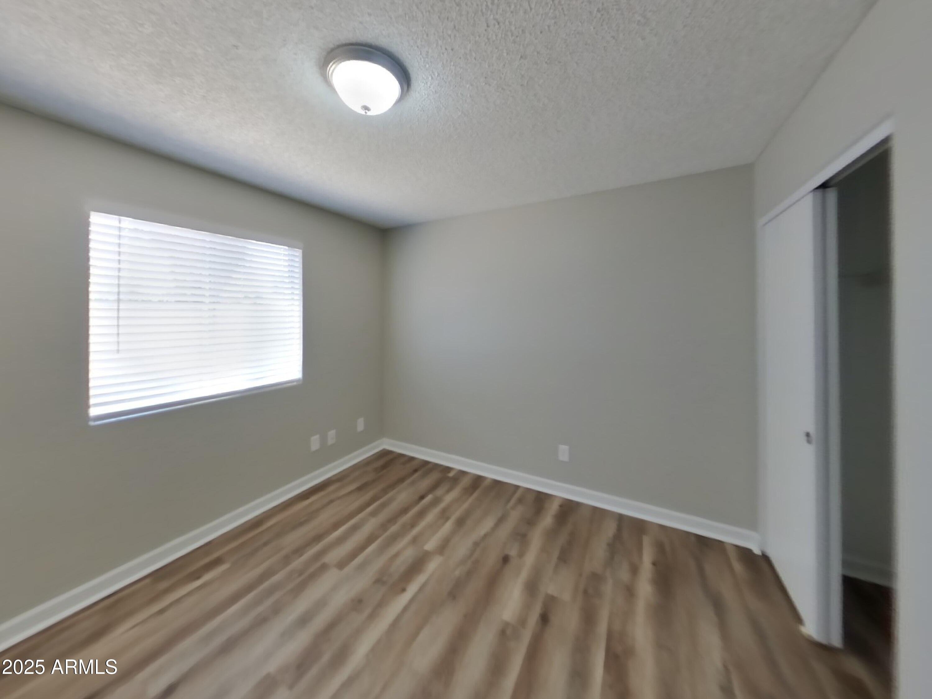 8948 West Heatherbrae Drive Phoenix, AZ 85037 - Photo 16 of 21 an empty room with wooden floor and windows