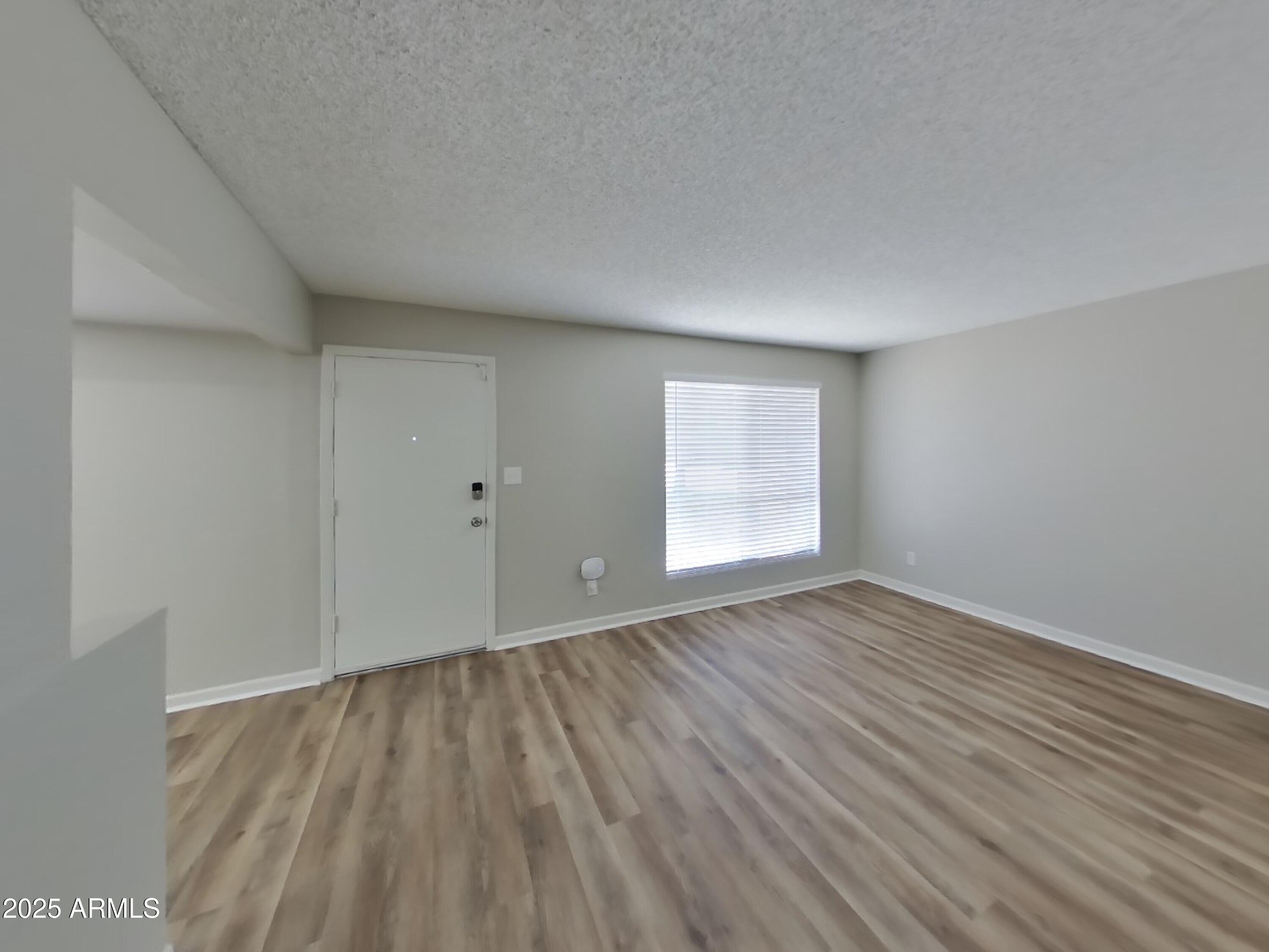 8948 West Heatherbrae Drive Phoenix, AZ 85037 - Photo 2 of 21 a view of an empty room with wooden floor and a window