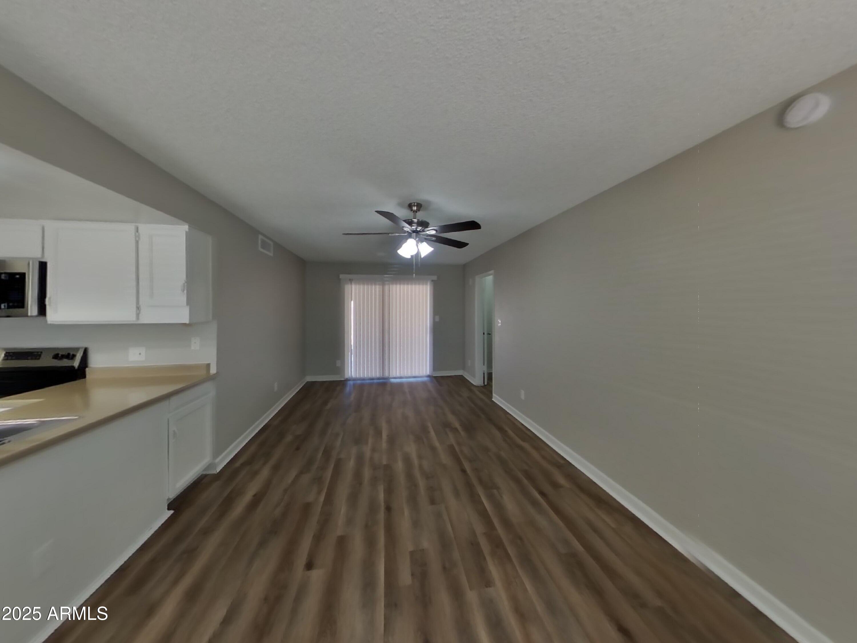 8948 West Heatherbrae Drive Phoenix, AZ 85037 - Photo 5 of 21 a view of empty room with wooden floor and fan