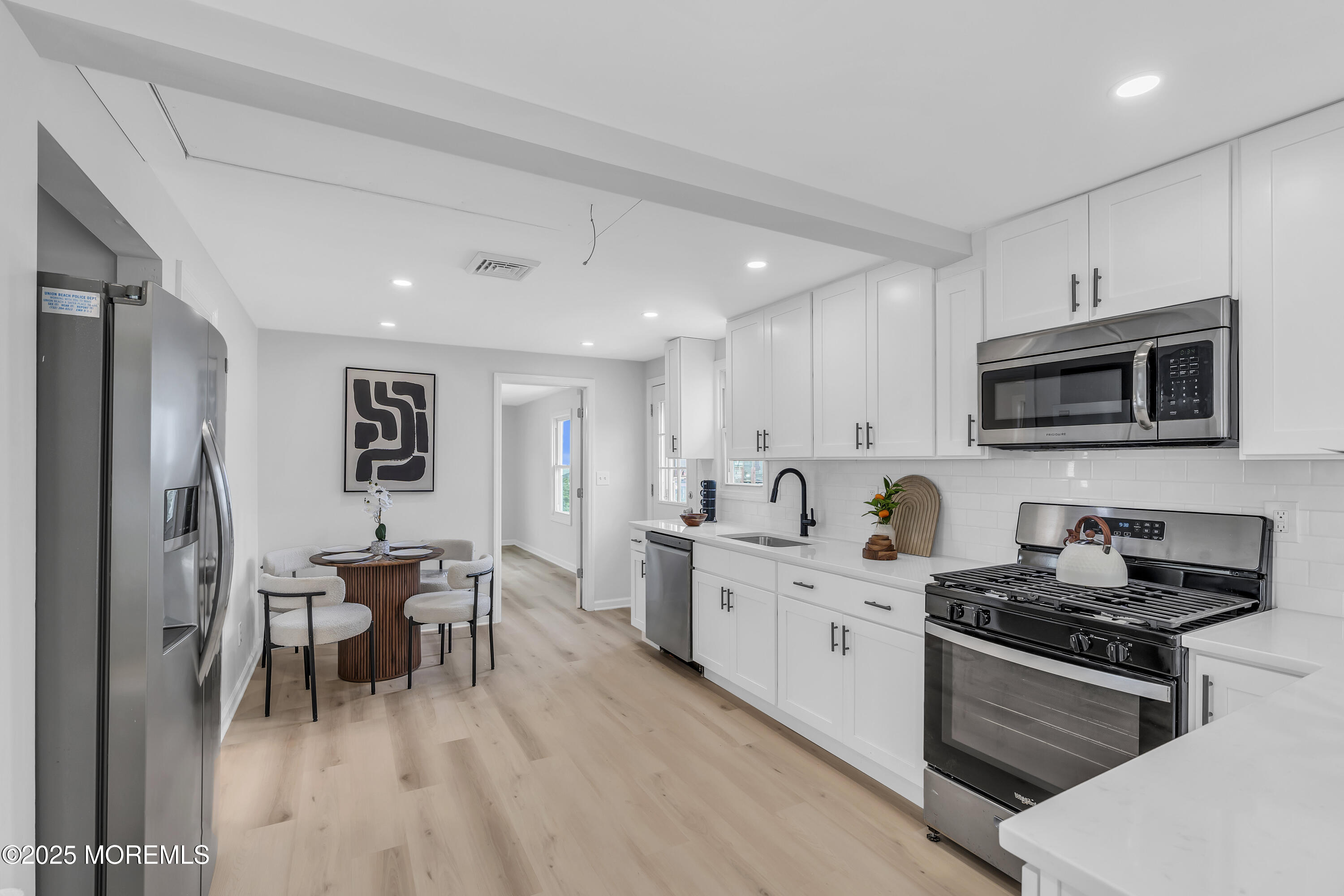 825 Lorillard Avenue Union Beach, NJ 07735 - Photo 5 of 22 a kitchen with stainless steel appliances kitchen island granite countertop a stove top oven a sink a dining table and chairs with wooden floor