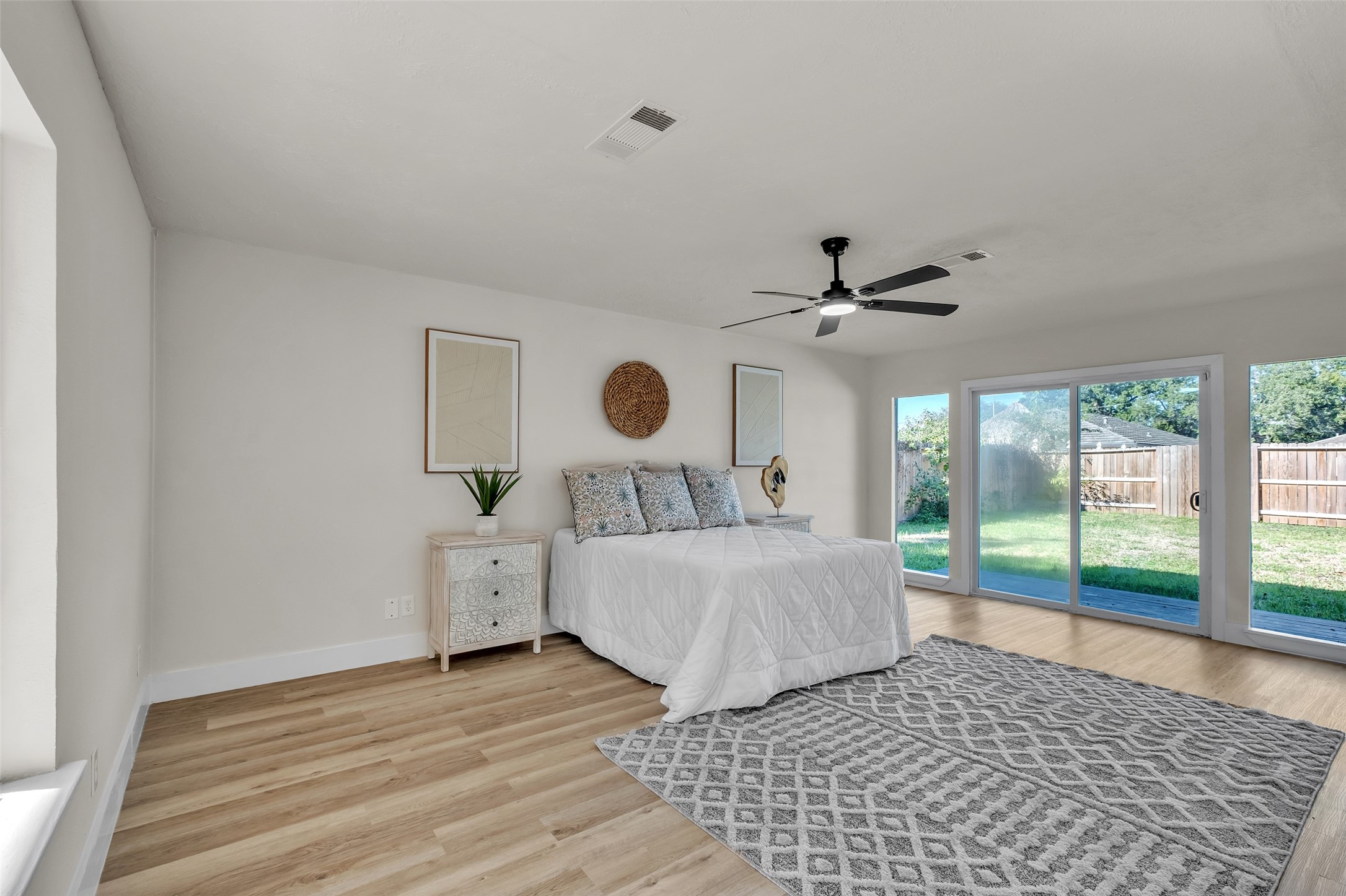 5502 Hewitt Drive Houston, TX 77092 - Photo 5 of 34 Spacious bedroom with large sliding glass doors leading to a backyard, offering abundant natural light. It includes a ceiling fan, light wood flooring, and neutral walls, creating a bright and airy atmosphere.