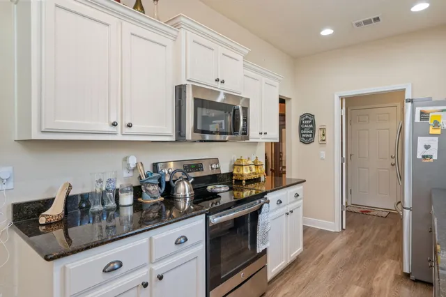 a kitchen with granite countertop white cabinets and stainless steel appliances