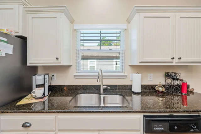 a kitchen with granite countertop a sink window and cabinets