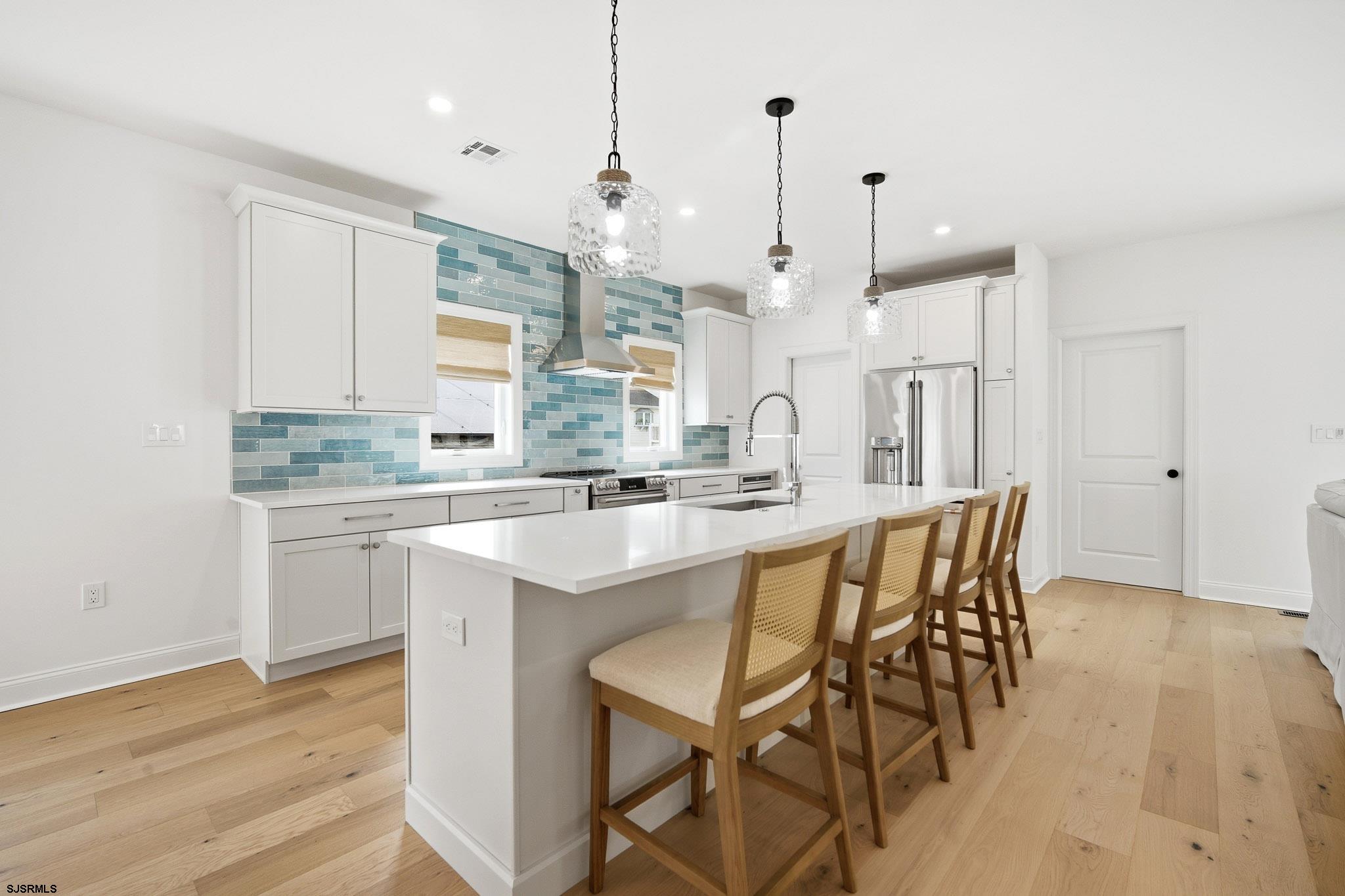 150 South 9th Brigantine, NJ 08203 - Photo 6 of 32 a kitchen with stainless steel appliances granite countertop a kitchen island a stove a sink a dining table and chairs with wooden floor
