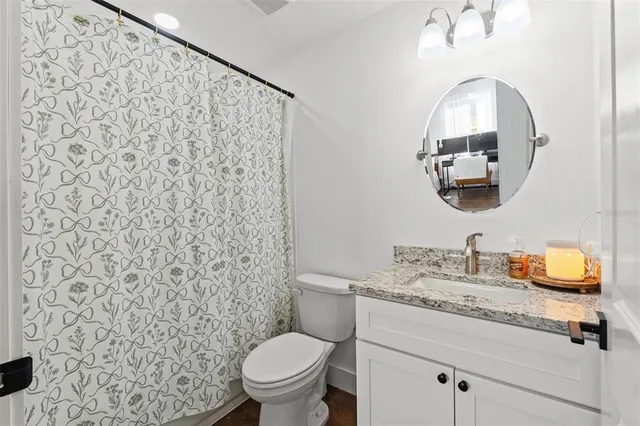 a bathroom with a granite countertop toilet sink and mirror