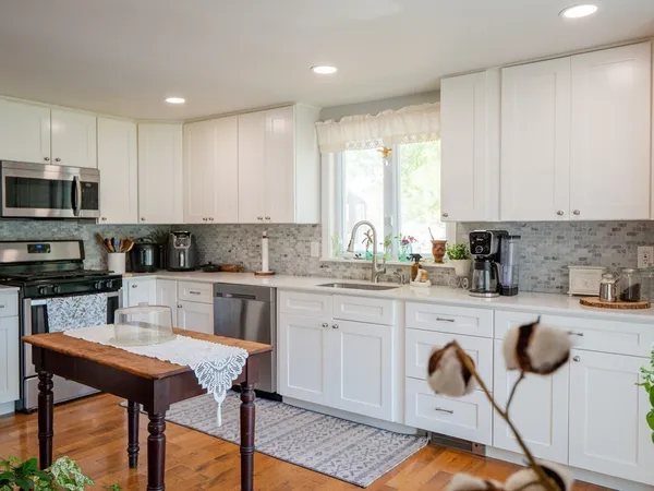 a kitchen with a stove a sink a microwave a dining table and chairs
