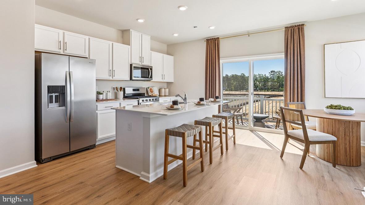 22 Baybreeze Drive Waretown, NJ 08758 - Photo 12 of 29 a kitchen with stainless steel appliances granite countertop a refrigerator a stove a sink a dining table and chairs with wooden floor