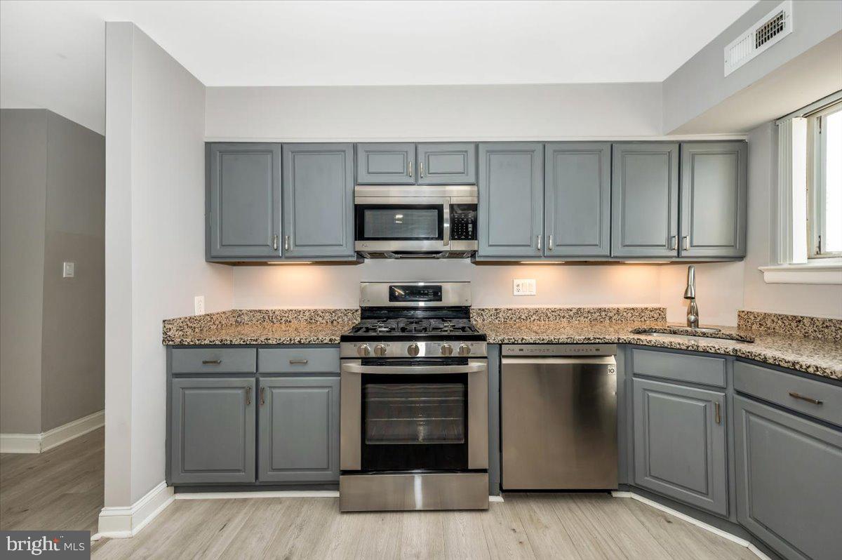 11368 Cherry Hill Road, Unit 1Q204 Beltsville, MD 20705 - Photo 8 of 46 a kitchen with granite countertop a stove top oven microwave and cabinets