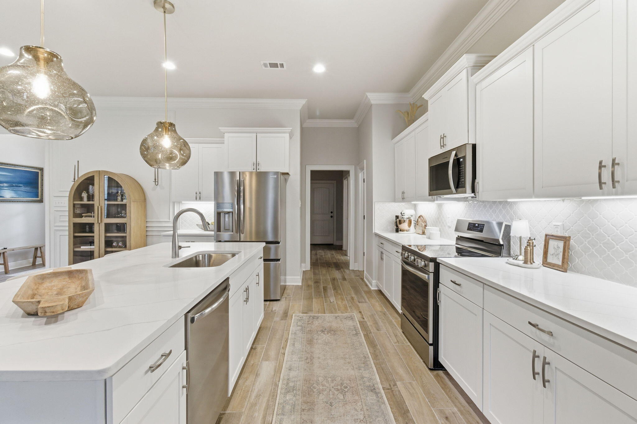 140 Flora Lane Freeport, FL 32439 - Photo 13 of 77 a large kitchen with a large island in the center a stove a oven a dining table and chairs with wooden floor