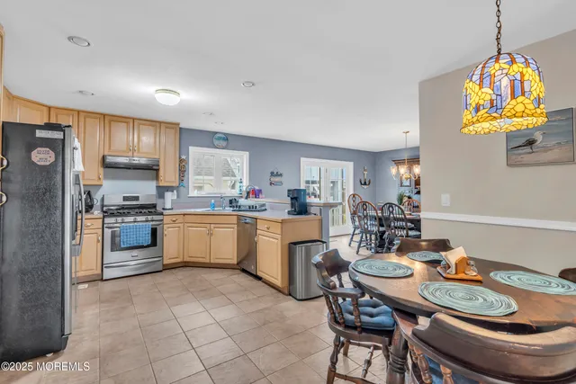 a kitchen with stainless steel appliances granite countertop a stove a sink a refrigerator a kitchen island with a dining table and chairs