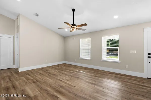 a view of empty room with wooden floor and ceiling fan