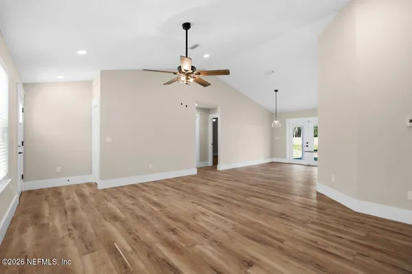 a view of an empty room with a window and wooden floor