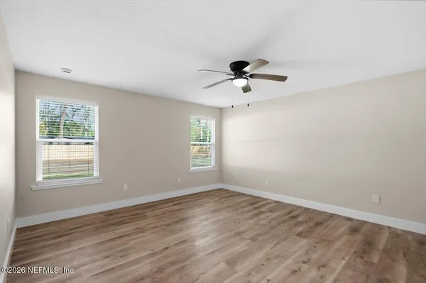 a view of empty room with wooden floor and ceiling fan