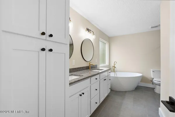 a bathroom with a granite countertop double vanity sink and a mirror