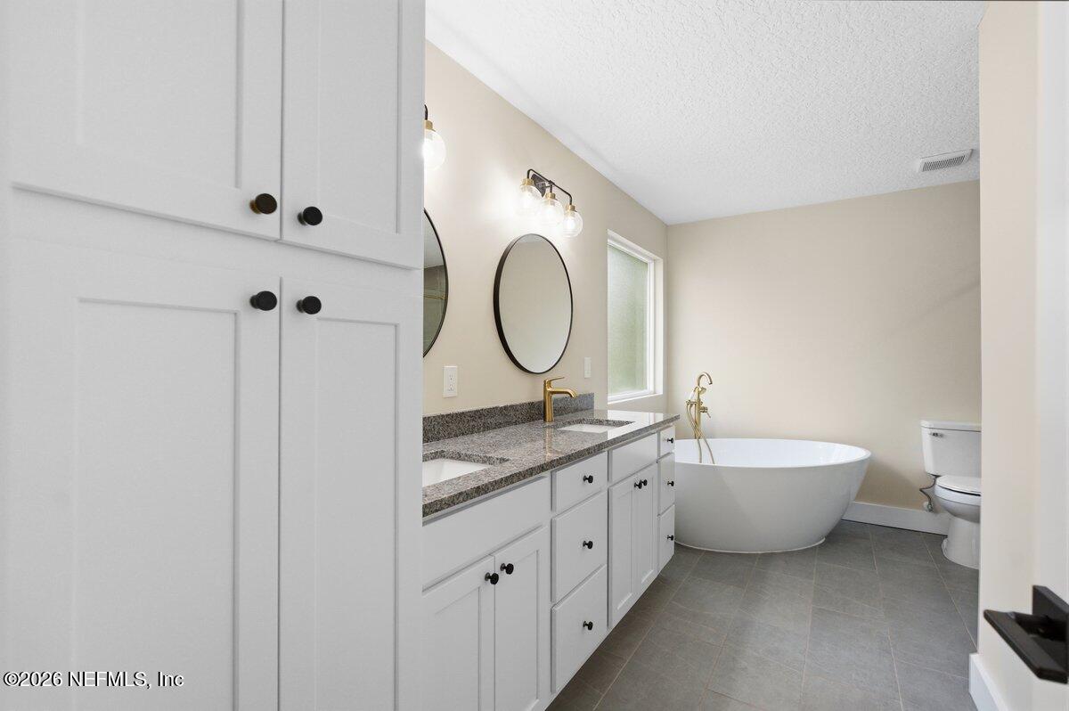 6093 Taylor Road Jacksonville, FL 32234 - Photo 20 of 44 a spacious bathroom with a double vanity sink a mirror and a bathtub