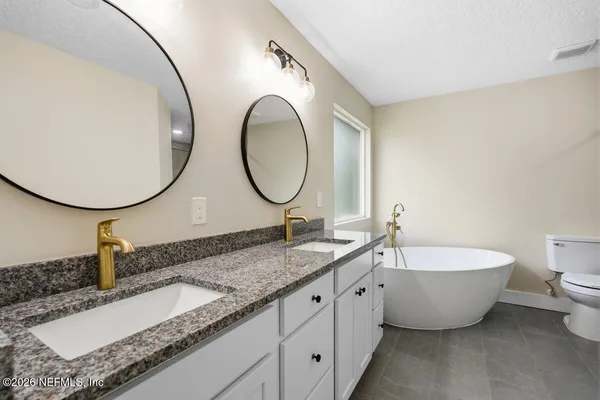 a bathroom with a granite countertop double vanity sink and a mirror
