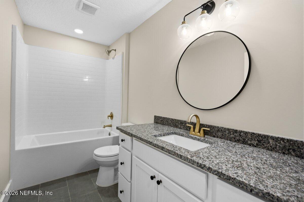 6093 Taylor Road Jacksonville, FL 32234 - Photo 27 of 44 a bathroom with a granite countertop toilet a sink and a mirror