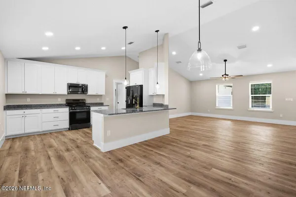 a large kitchen with stainless steel appliances a large counter top a wooden floors a fireplace and a window