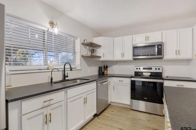 a kitchen with stainless steel appliances granite countertop a sink a stove and cabinets
