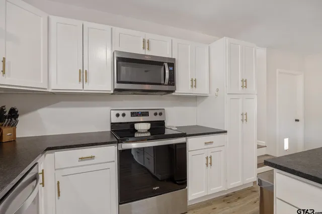 a kitchen with white cabinets and black appliances