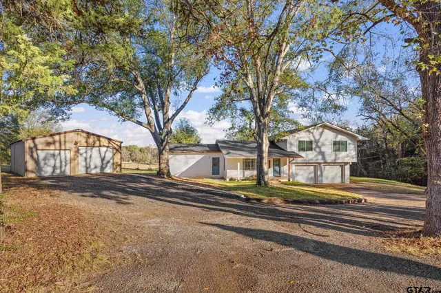 a small white house with a large tree next to a yard