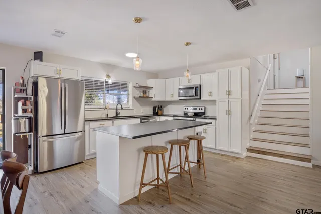 a kitchen with stainless steel appliances granite countertop a refrigerator and a stove top oven