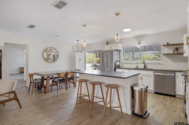 a kitchen with stainless steel appliances granite countertop a kitchen island a stove a table and chairs