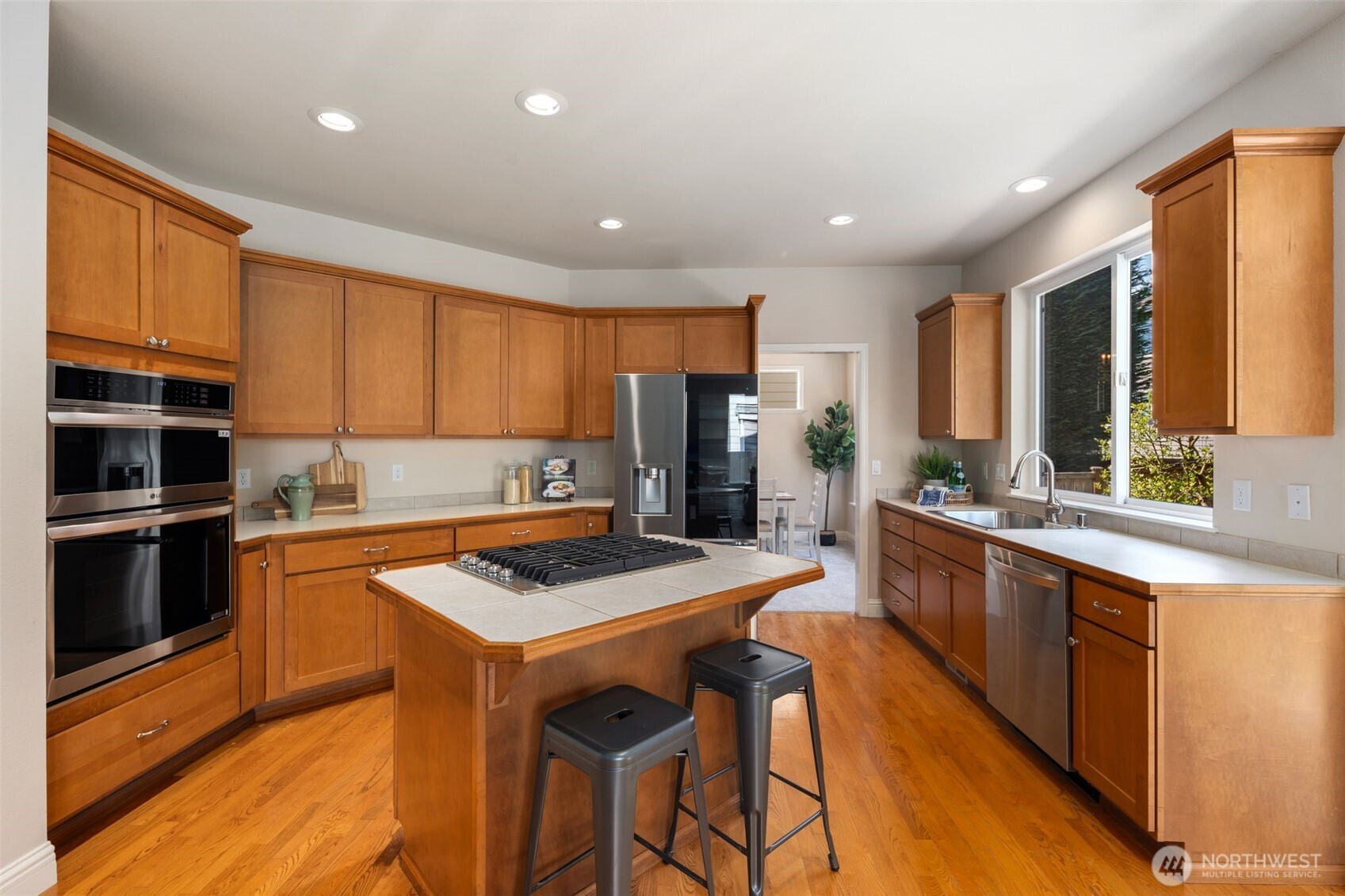 18523 173rd Street Southeast Renton, WA 98058 - Photo 8 of 40 a kitchen with stainless steel appliances granite countertop a refrigerator a stove top oven a sink dishwasher and wooden cabinets with wooden floor
